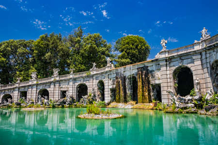 July 3, 2020 - Royal Palace of (Reggia di) Caserta - The large fountain of Aeolus with arches and marble statues. The water flows from above into a small waterfall. Fish in the big basin. Blue sky.のeditorial素材