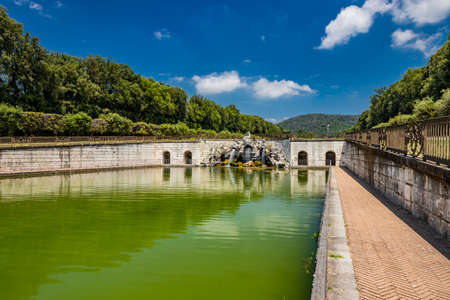 July 3, 2020 - Royal Palace of (Reggia di) Caserta - The large fountain of Aeolus with arches and marble statues. The water flows from above into a small waterfall. Fish in the big basin. Blue sky.のeditorial素材