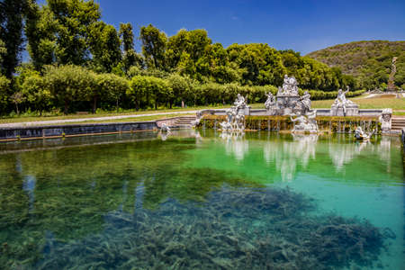 July 3, 2020 - Royal Palace of (Reggia di) Caserta - The large fountain of Aeolus with arches and marble statues. The water flows from above into a small waterfall. Fish in the big basin. Blue sky.のeditorial素材