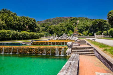 July 3, 2020 - Royal Palace of (Reggia di) Caserta - The very long basin of the park's artificial lake. The perspective view. The marble statues look and extend their hand towards the palace. Blue skyのeditorial素材