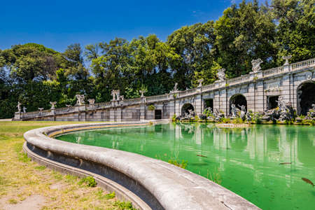 July 3, 2020 - Royal Palace of (Reggia di) Caserta - The very long basin of the park's artificial lake. The perspective view. The marble statues look and extend their hand towards the palace. Blue skyのeditorial素材