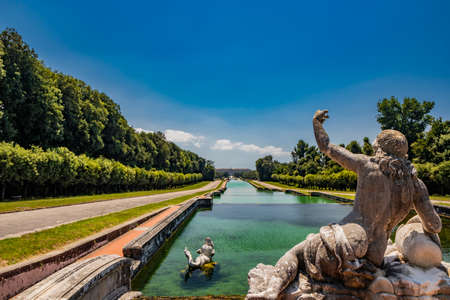 July 3, 2020 - Royal Palace of (Reggia di) Caserta - The very long basin of the park's artificial lake. The perspective view. The marble statues look and extend their hand towards the palace. Blue skyのeditorial素材