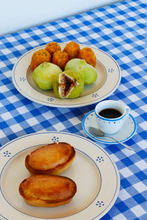 Breakfast in Salento, with typical products of the southern Italian tradition: Prickly pears, figs and Pasticciotto with cream on ceramic plates and white and blue checked tablecloth.の写真素材