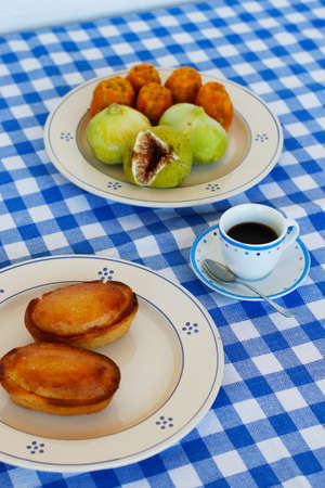 Breakfast in Salento, with typical products of the southern Italian tradition: Prickly pears, figs and Pasticciotto with cream on ceramic plates and white and blue checked tablecloth.の写真素材