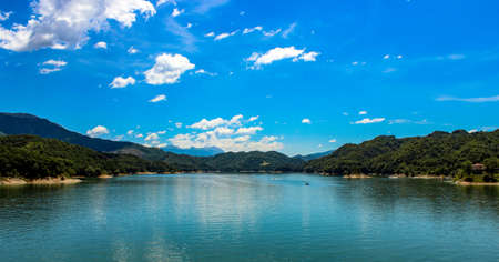 The lake of Salto, the largest artificial lake in Lazio, in the province of Rieti and created by damming the Salto river with the Salto dam. A sportsman practices water skiing towed by a motorboat.の写真素材