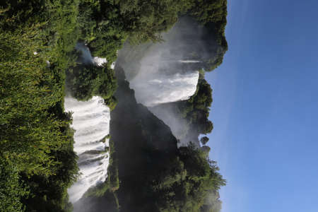 The Cascata delle Marmore or Marmore Falls, in the Nera River valley, in Terni, Umbria, Italy. The strong jet of water generates foam and steam. The blue sky in summer.の写真素材