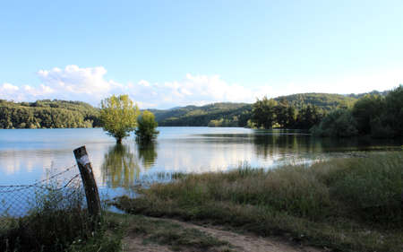 The tables of a hotel for breakfast by the lake. View of the Scandarello lake, in Amatrice, in the province of Rieti, in Lazio, Italy. The blue sky in summer. the green mountains in the background.のeditorial素材