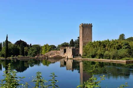The Garden of Ninfa is a landscape garden in the territory of Cisterna di Latina, in the province of Latina, central Italy. View from the lake of the ruins of the ancient medieval castle.のeditorial素材