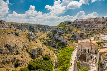 Matera, Basilicata, Italy - Panoramic view through a small slit, window, of the Sassi of Matera, Barisano and Caveoso. The ancient houses of stone and brick, carved into the rock. The ravine below.の写真素材