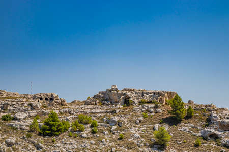 Matera, Basilicata, Italy - Panoramic view through a small slit, window, of the Sassi of Matera, Barisano and Caveoso. The ancient houses of stone and brick, carved into the rock. The ravine below.の写真素材