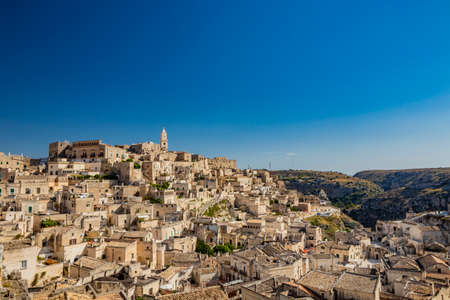 Matera, Basilicata, Italy - Panoramic view through a small slit, window, of the Sassi of Matera, Barisano and Caveoso. The ancient houses of stone and brick, carved into the rock. The ravine below.の写真素材