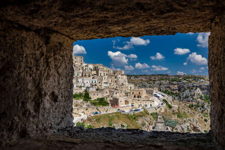 Matera, Basilicata, Italy - Panoramic view through a small slit, window, of the Sassi of Matera, Barisano and Caveoso. The ancient houses of stone and brick, carved into the rock. The ravine below.の写真素材