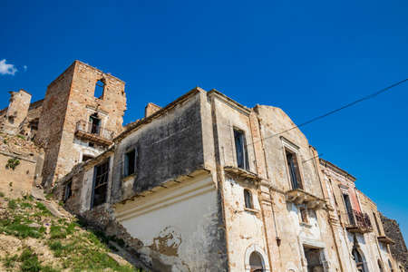 Craco, Matera, Basilicata, Italy. Ghost town destroyed and abandoned following a landslide. Collapsed houses and the remains invaded by vegetation. Broken walls, windows and doors, crumbling balconiesのeditorial素材