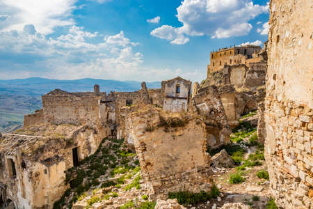 Craco, Basilicata, Italy. Ghost town destroyed and abandoned following a landslide. Collapsed houses and the remains invaded by vegetation. Broken walls, windows and doors. Bell tower of the churchのeditorial素材
