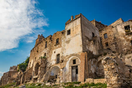 Craco, Basilicata, Italy. Ghost town destroyed and abandoned following a landslide. Collapsed houses and the remains invaded by vegetation. Broken walls, windows and doors. Bell tower of the churchのeditorial素材