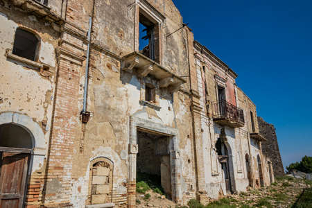 Craco, Matera, Basilicata, Italy. Ghost town destroyed and abandoned following a landslide. Collapsed houses and the remains invaded by vegetation. Broken walls, windows and doors, crumbling balconiesのeditorial素材