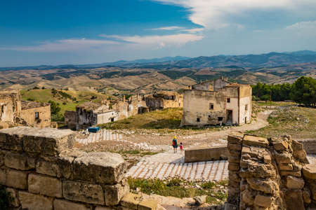 Craco, Basilicata, Italy. Ghost town destroyed and abandoned following a landslide. Collapsed houses and the remains invaded by vegetation. Broken walls, windows and doors. Bell tower of the churchのeditorial素材