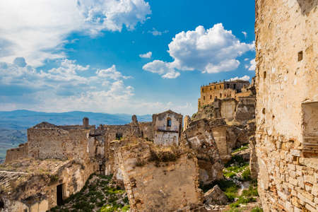 Craco, Basilicata, Italy. Ghost town destroyed and abandoned following a landslide. Collapsed houses and the remains invaded by vegetation. Broken walls, windows and doors. Bell tower of the churchのeditorial素材