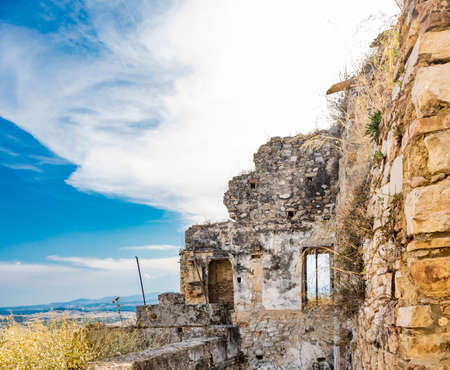 Craco, Basilicata, Italy. Ghost town destroyed and abandoned following a landslide. Collapsed houses and the remains invaded by vegetation. Broken walls, windows and doors. Bell tower of the churchのeditorial素材