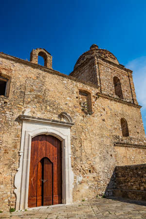 Craco, Basilicata, Italy. Ghost town destroyed and abandoned following a landslide. Collapsed houses and the remains invaded by vegetation. Broken walls, windows and doors. Bell tower of the churchのeditorial素材