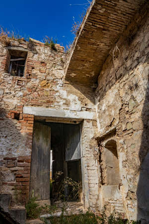 Craco, Basilicata, Italy. Ghost town destroyed and abandoned following a landslide. Collapsed houses and the remains invaded by vegetation. Broken walls, windows and doors. Bell tower of the churchのeditorial素材