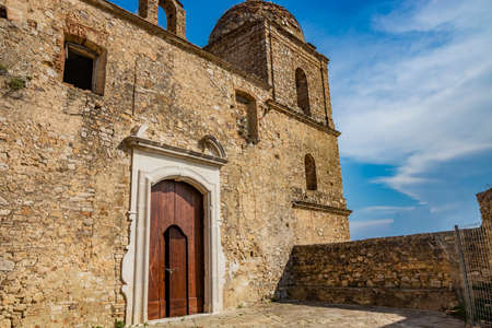 Craco, Basilicata, Italy. Ghost town destroyed and abandoned following a landslide. Collapsed houses and the remains invaded by vegetation. Broken walls, windows and doors. Bell tower of the churchのeditorial素材