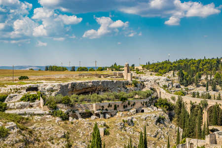 Gravina in Puglia, Italy. The stone bridge, ancient aqueduct and viaduct, over the Gravina stream. The Madonna della Stella Sanctuary, with its bell tower and the ancient cave church.の写真素材
