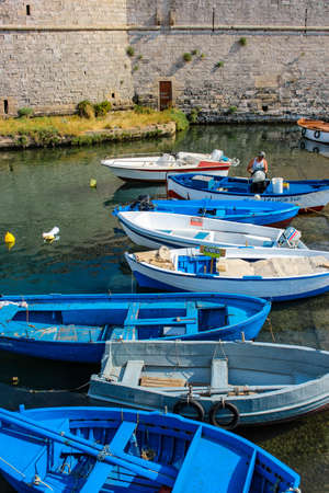 The castle fortress overlooking the sea, in the town of Gallipoli, in Puglia, Italy. The boats moored. The blue sky.のeditorial素材