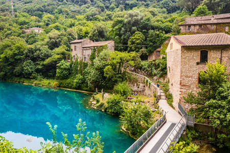 A glimpse of the small village of Stifone, on the Nera river. Umbria, Terni, Italy. The walls of stones and bricks. The bridge over the river with clear blue waters. Tourists stroll through the alleysの写真素材