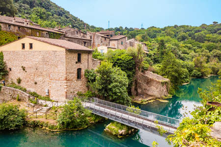 A glimpse of the small village of Stifone, on the Nera river. Umbria, Terni, Italy. The walls of stones and bricks. The bridge over the river with clear blue waters. Tourists stroll through the alleysの写真素材