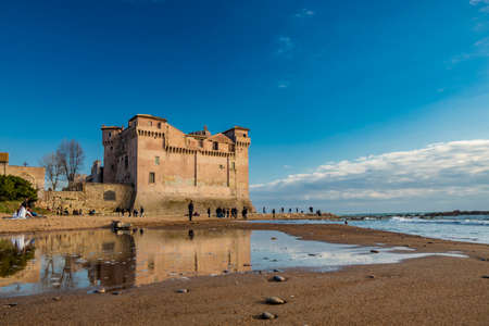 March 14, 2022 - Santa Marinella, Rome, Lazio, Italy - The seaside castle of Santa Severa on a winter day. The rough sea, wind, the cloudy blue sky. Many people stroll and enjoy the sun on the beach.のeditorial素材