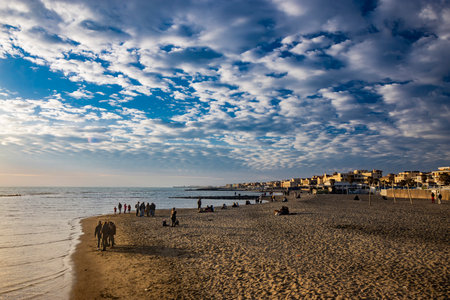 February 12, 2023 - Ostia, Rome, Italy. The sea of Ostia, on the Roman coast, on a winter Sunday. People enjoy the public holiday by walking on the beach in the open air in the evening.のeditorial素材