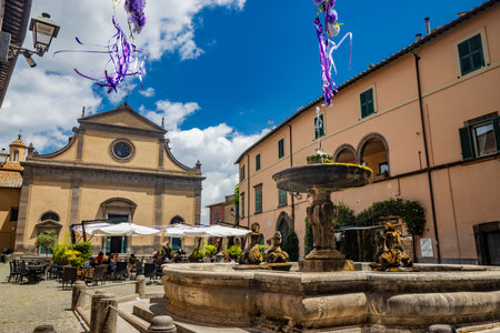 July 2, 2023 - Tuscania, Viterbo, Lazio. A glimpse of the ancient medieval village of Tuscania, city of the Etruscans. The square with the church and the large fountain.のeditorial素材