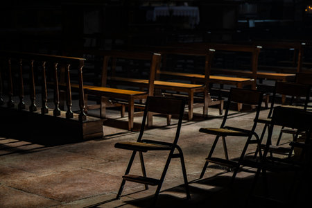 The dark and silent interior of an ancient church, with light filtering through the rose window,...