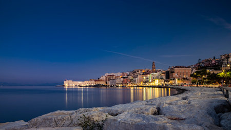 Gaeta, Latina, Lazio, Italy. A splendid night view of the city. The old town with its houses overlooking the sea. The waterfront and the lights of the harbor reflecting on the water.の写真素材