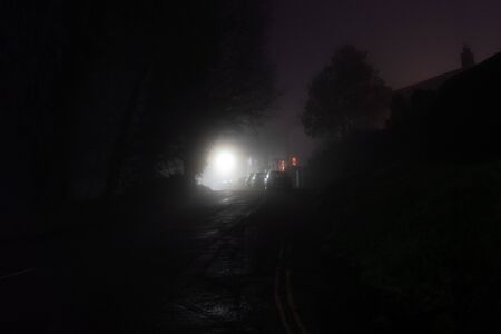 Looking up a rural street with houses next to a street light on a dark, misty, winters night.