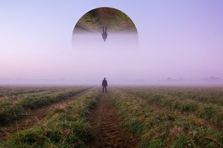 A science fiction concept. A man standing in a field looking out across space with a reflected...