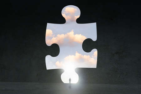 A puzzle concept, of a man silhouetted against a jigsaw puzzle and cloudsの写真素材