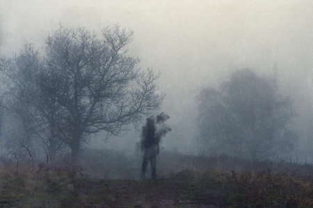 A haunted figure disintegrating on a path on a hill on a moody, foggy winters day. With an abstract,...