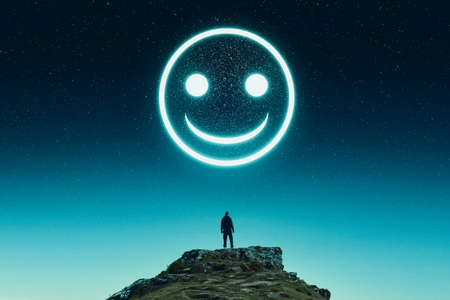 A  social media, mental health concept. Of a figure looking at a sinister emoji smiling face glowing in the sky.の写真素材