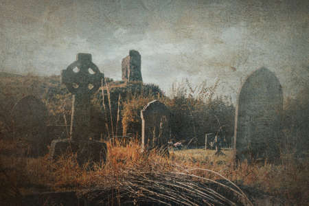 A spooky graveyard in the countryside. With a ruin in the distance. With a grunge editの写真素材