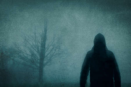 A spooky concept. Of a blurred, hooded figure. Standing in the countryside. On a bleak, moody...