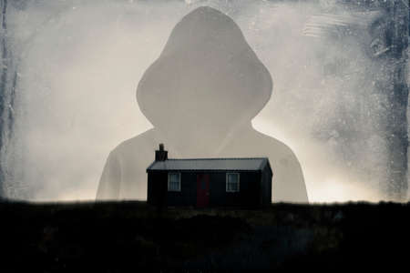 A horror concept of a spooky double exposure of a hooded figure. And a small isolated hut on a hill....