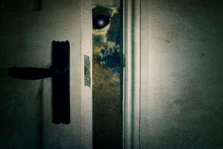 A scary zombie like demon looking through an open door way in a spooky horror house. With an old grunge texture.の写真素材