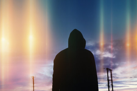 A mystical, science fiction concept of a man looking up at mysterious glowing UFO lights in the skyの写真素材