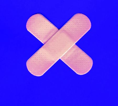 Two plasters forming a cross on blue backgroundの写真素材