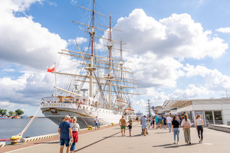 Tourists walk around the marina near sailing ship Dar Pomorza (Gdynia, Poland)