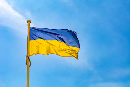 Ukraine flag on the pole on the sky background