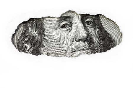 Benjamin Franklin macro peeking through torn white paper.の写真素材