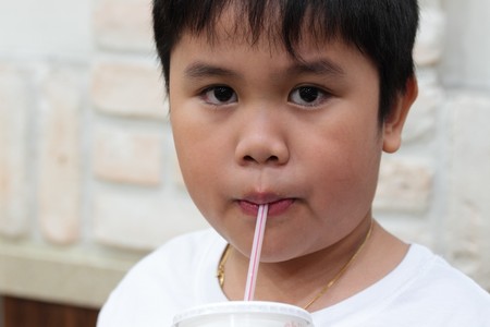 Boy sipping a soft-drink in a brickwall  backgroundの写真素材